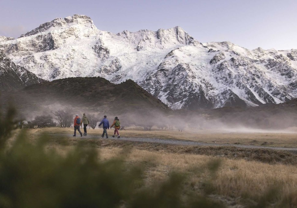 Walkers on the Hooker Valley Track below snow-covered mountains in Aoraki Mount Cook National Park